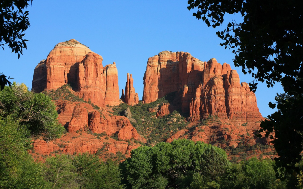 Towering red rocks framed by trees in Sedona, AZ.