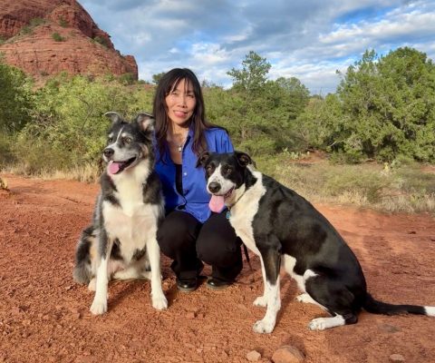 Gina Lee with her two black and white dogs posing for a photo on Sugarloaf trail in Sedona, AZ.